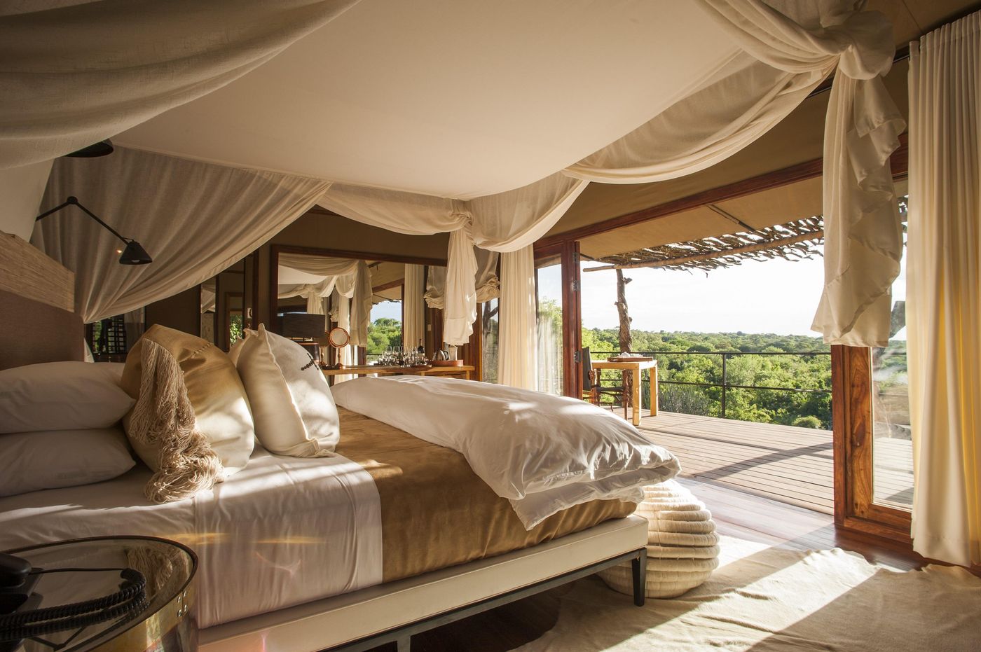 A tented bedroom at Mwiba Lodge with white drapes open to a view over the savanna, Tanzania