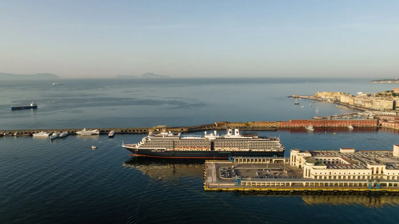 A cruise ship berthed at the passenger terminal in the port of Naples, seen from above, with the bay behind